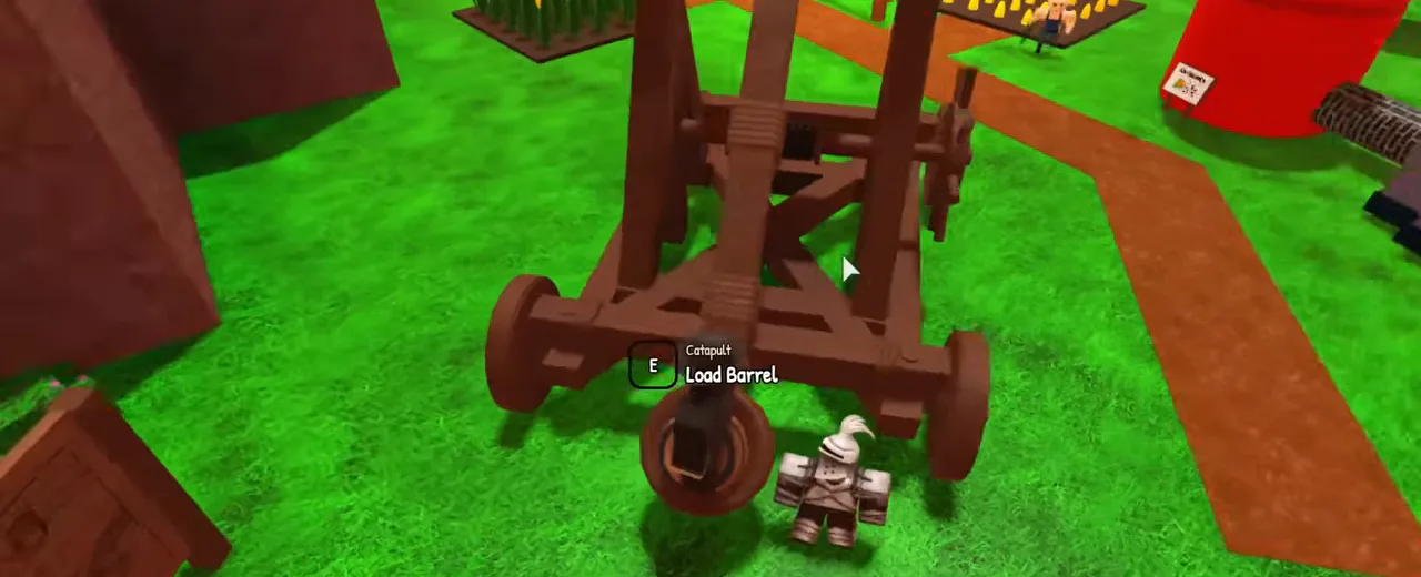 An empty wooden catapult on grass with a Load Barrel prompt beside it