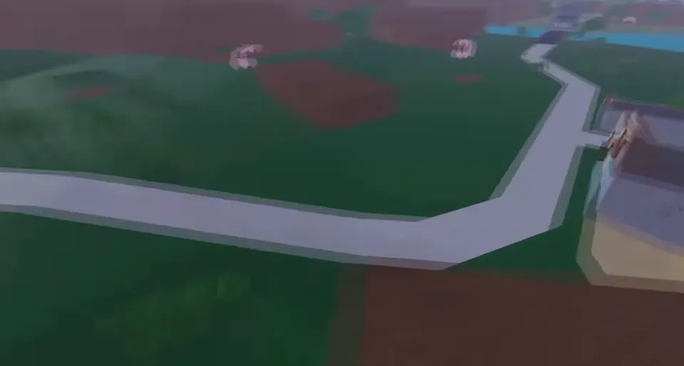 A high view over green land with a winding pale road, pink trees and a river in the distance